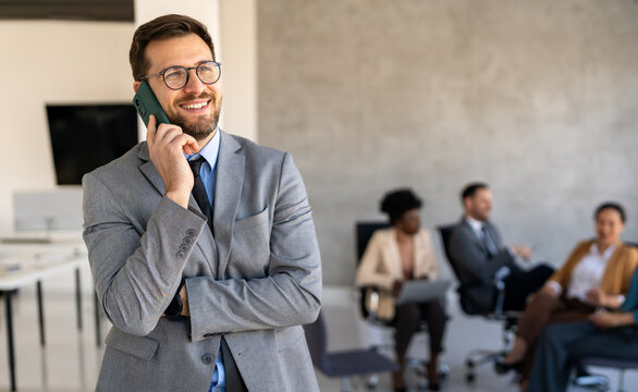 A confident business man leads her busy office life, multitasking with smartphone communication