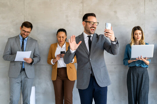 A confident business man leads her busy office life, multitasking with smartphone communication