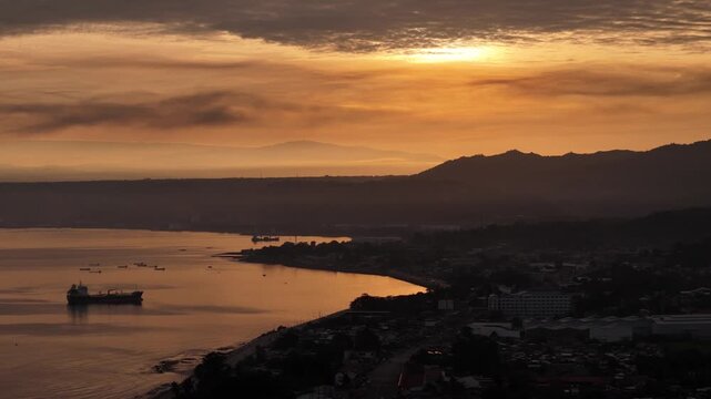 Aerial sideways flight over Macajalar Bay facing sunrise-lit clouds on the eastern horizon in Cagayan de Oro, Philippines