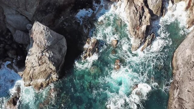 Vertical drone over surf churning between lava sea stacks VFX plate for coastal storytelling, Flores, Azores