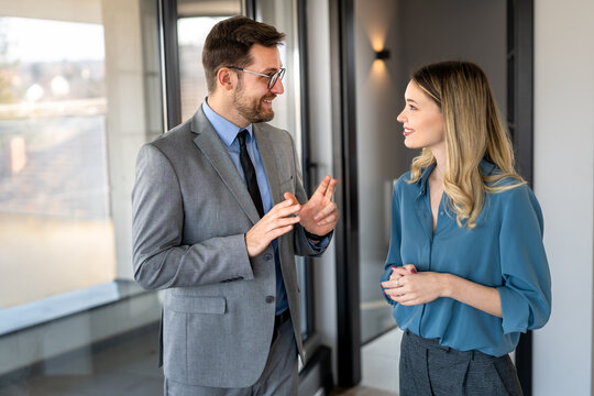 Two happy diverse multiethnic business team people working, talking in corporate office