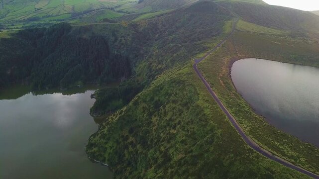 Drone glides above two adjacent crater lakes split by narrow ridge establishing shot, Flores, Azores