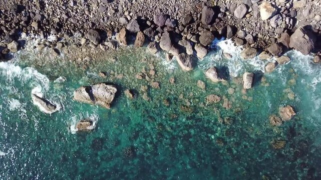 Top-down over turquoise tidepool meeting lava boulder shore scene setter, Costa do Lajedo, Flores
