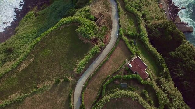 High aerial over lighthouse promontory with switchback road meeting Atlantic opener, S&Atilde;&pound;o Miguel, Azores