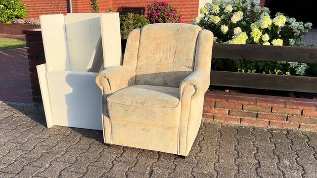 Old armchair and wooden cabinet left on sidewalk for bulky waste collection in Germany