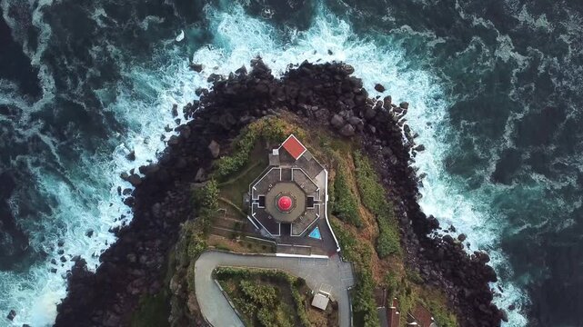 Symmetrical top-down on lighthouse as waves frame rocky point mood shot for travel edits, S&Atilde;&pound;o Miguel, Azores