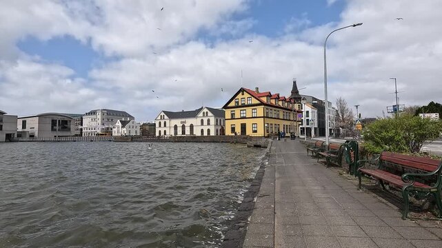 Tj&Atilde;&para;rnin lake waterfront with I&Atilde;&deg;n&Atilde;&sup3; building and historic yellow facade, seagulls, Reykjavik, Iceland