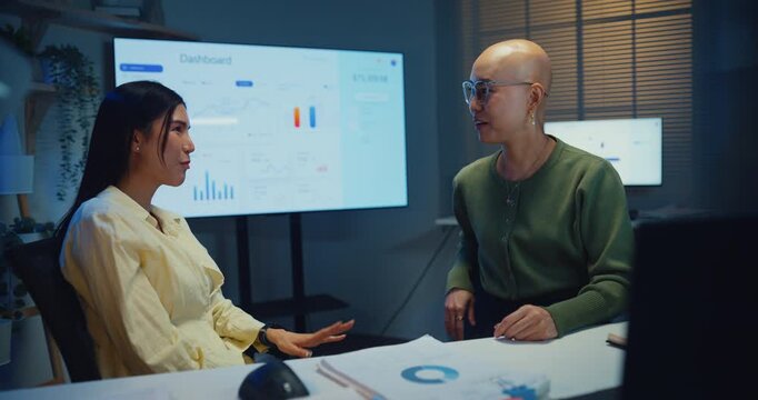 Happy young Asian co-worker team smile and brainstorm together in dark office at night. Employee overtime overwork, professional cooperation trust, corporate business goal motivation care concept.