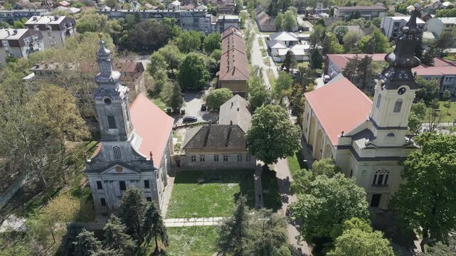 Forward drone flight capturing two prominent historic churches in the heart of Vrbas town, northern Serbia.