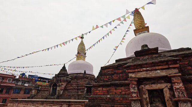 Chilancho Stupa compound, two white domed stupas with gold spires and Buddha eyes, prayer flags above, Kirtipur, Nepal
