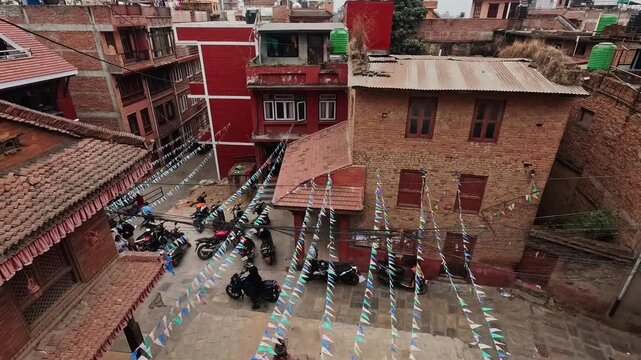 Kirtipur overhead shot of stepped alley with festival bunting flags, parked motorbikes on cobblestone below, Nepal
