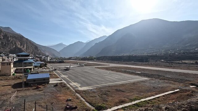 Twin propeller aircraft taxiing Jomsom airport runway mountains Mustang Nepal valley