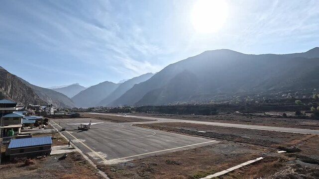 Small propeller plane Jomsom airport runway taking off Nilgiri Mountain in the background. village snow peaks Mustang Nepal valley