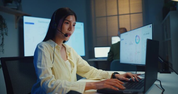 Team young Asian businesswoman working late talk on telephone headset in call center office at night. Corporate customer service support, telemarketing, finance insurance investment advisor concept.