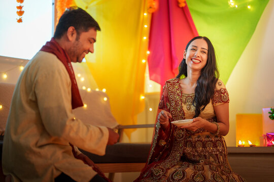 Happy Indian couple celebrating Diwali festival at decorated home for cultural tradition