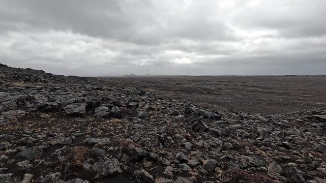 Desolate black lava ridge at tectonic plate boundary, flat volcanic plain to horizon, Reykjanes, Iceland