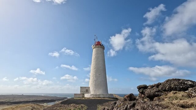 Reykjanesviti lighthouse against blue sky with black lava rocks and Atlantic coastline, Reykjanes, Iceland