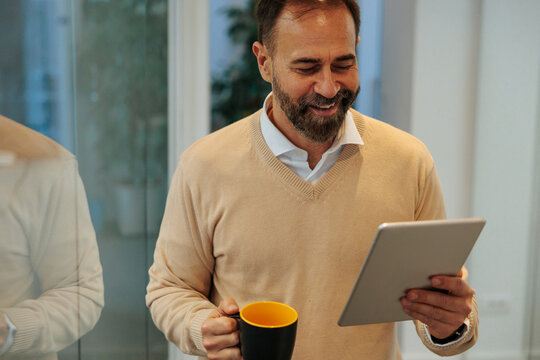 Mature man engaging with tablet and enjoying coffee