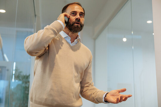 Business man talking on smartphone making gestures at office