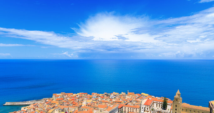 Panoramic view of an ancient coastal town with terracotta roofs overlooking the blue sea
