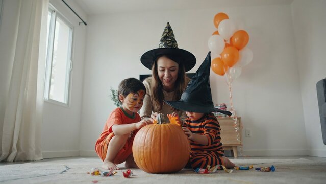 Family halloween fun mother and sons carving a pumpkin indoors