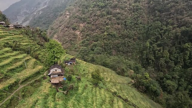 Aerial slide over village rooftops and terraces toward the Jhinu Danda suspension bridge, Annapurna Base Camp trek, Nepal