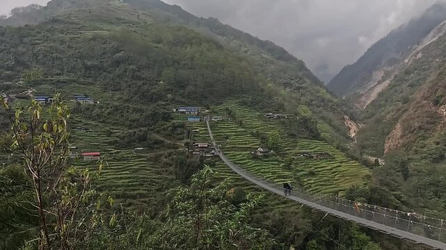 Push toward the long Jhinu Danda suspension bridge crossing the valley above rice terraces, Annapurna Base Camp trek, Nepal
