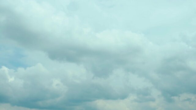 Wide view of layered stratocumulus and cumulus clouds filling sky with dense billowy forms, muted cyan blue tones, cool diffuse light, soft texture, calm atmospheric mood, faint airborne silhouette