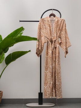 Luxury  kimono robe hanging on minimalist clothing rack with tropical plant