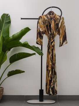 Luxury  kimono robe hanging on minimalist clothing rack with tropical plant