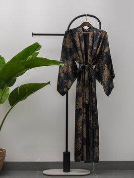 Luxury  kimono robe hanging on minimalist clothing rack with tropical plant