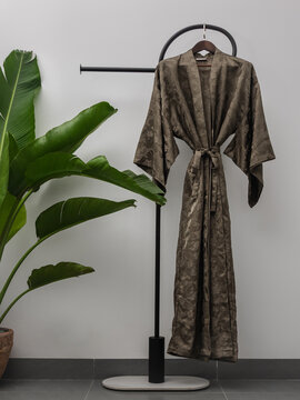 Luxury  kimono robe hanging on minimalist clothing rack with tropical plant