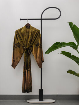 Luxury  kimono robe hanging on minimalist clothing rack with tropical plant