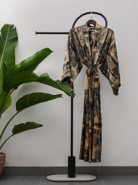 Luxury  kimono robe hanging on minimalist clothing rack with tropical plant