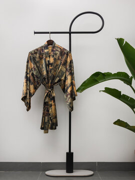 Luxury  kimono robe hanging on minimalist clothing rack with tropical plant