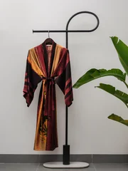 Luxury  kimono robe hanging on minimalist clothing rack with tropical plant © blackday