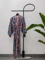 Luxury  kimono robe hanging on minimalist clothing rack with tropical plant © blackday