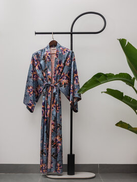 Luxury  kimono robe hanging on minimalist clothing rack with tropical plant
