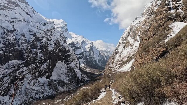 Walking down the rocky valley trail below MBC between towering snow peaks, Nepal