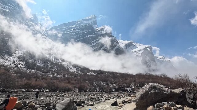 Fog races up the Modi Khola riverbed valley below towering snow peaks, Annapurna, Nepal