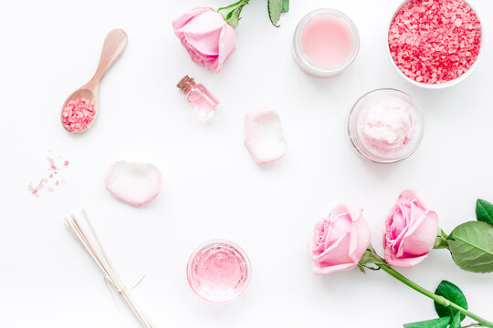 cosmetic set with rose blossom and body cream on white desk background top view