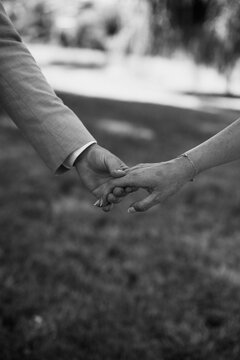Mari&eacute;s se tenant la main lors d&rsquo;une c&eacute;r&eacute;monie de mariage en plein air, en noir et blanc
