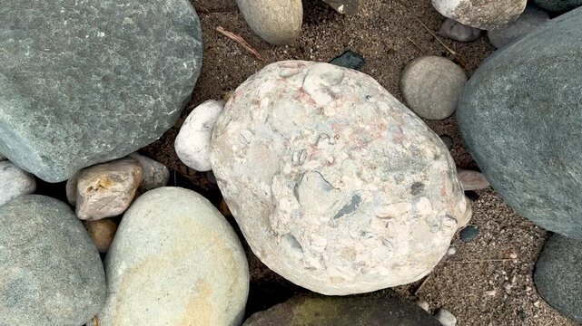 Closeup of various textured stones and pebbles on a sandy surface in natural earthy tones