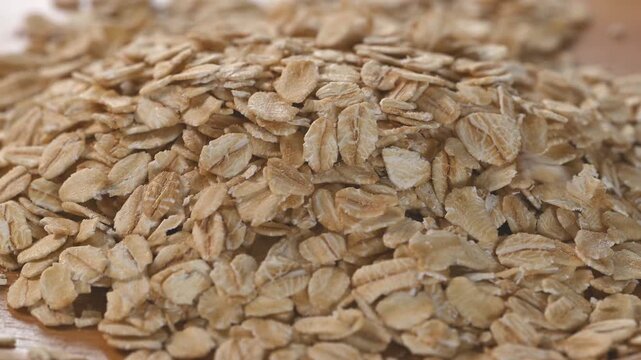 Close-up of dried rolled oat flakes pouring on pile