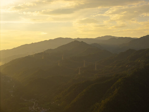 The sun sets over the green mountain ranges of the rural countryside in China as light shines across the rolling hills and the valley below