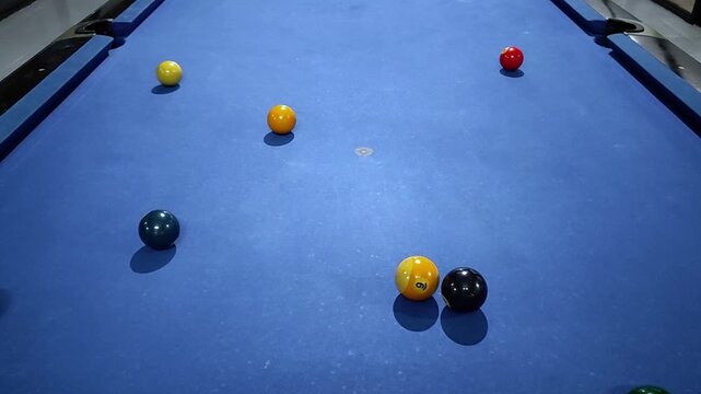 Pool balls arranged on a blue billiard table before a break shot. Close-up footage capturing the start of a billiards game as the balls scatter across the table.