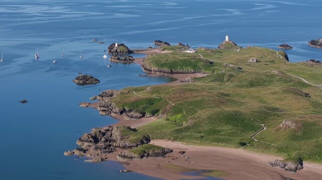 Gentle left to right pan from a high drone over Llanddwynn lighthouse