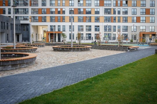 Courtyard plaza with paved pathway and round wooden benches near apartment buildings
