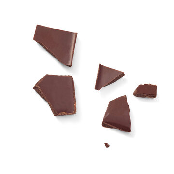 Several irregular pieces of dark chocolate are scattered across a white background. Chocolate pieces isolated. Top view.