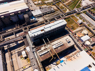 Fototapeta premium View of industrial complex with pipelines and buildings taken from above during daylight hours in an urban setting